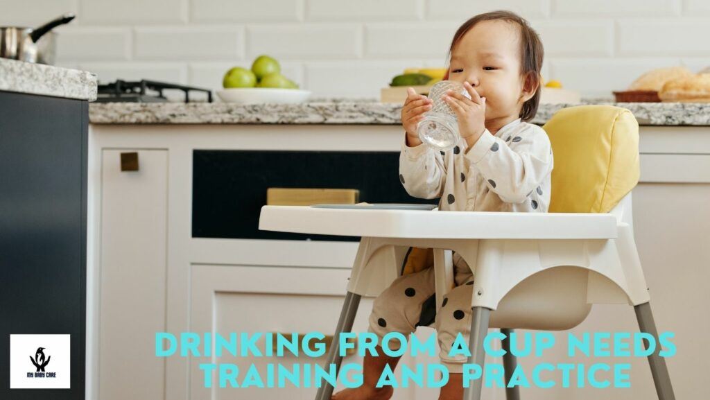 baby drinking with a cup in an feeding chair.